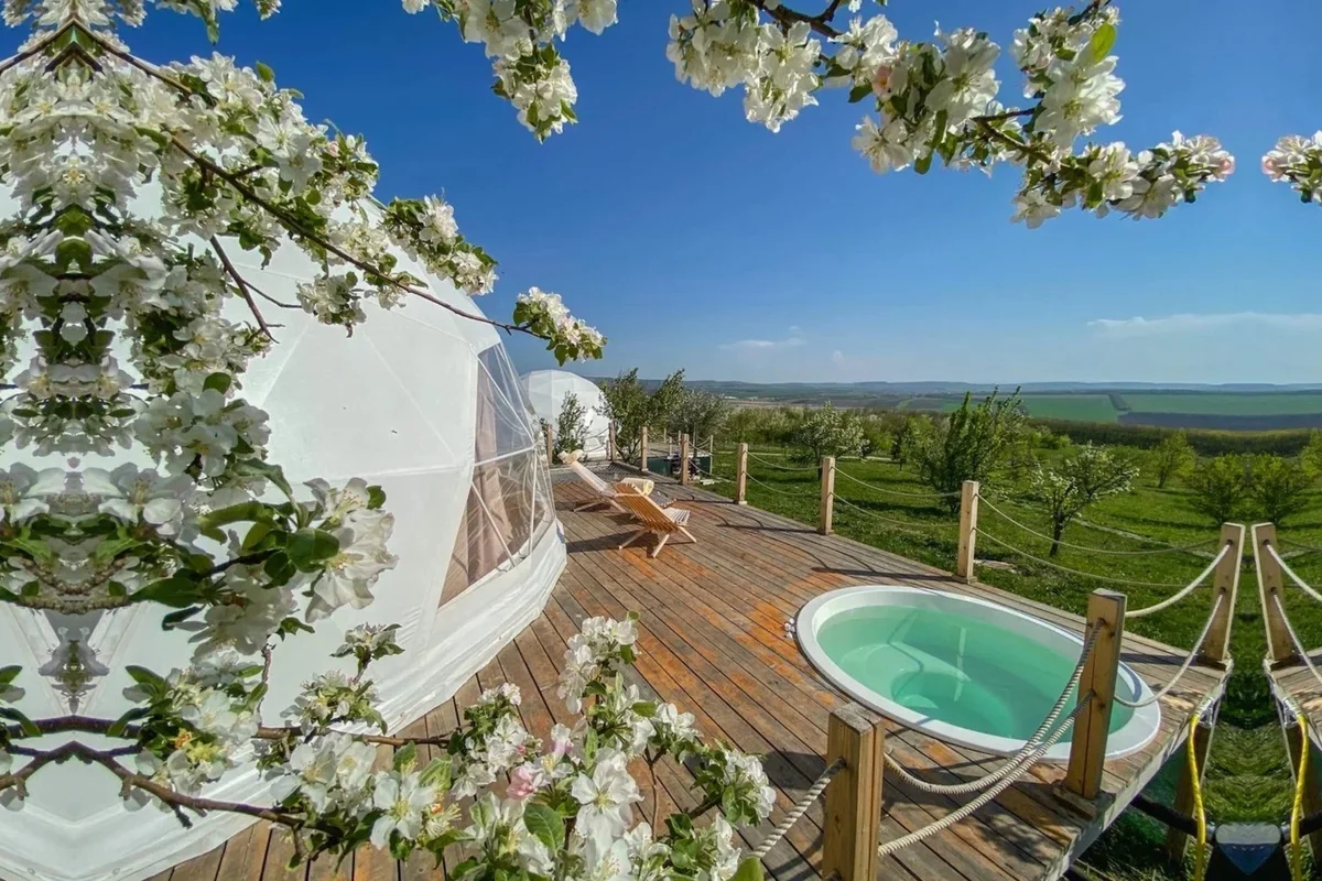 Kupola za glamping sa privatnom terasom i jacuzzijem, postavljena u prirodnom ambijentu sa pogledom
