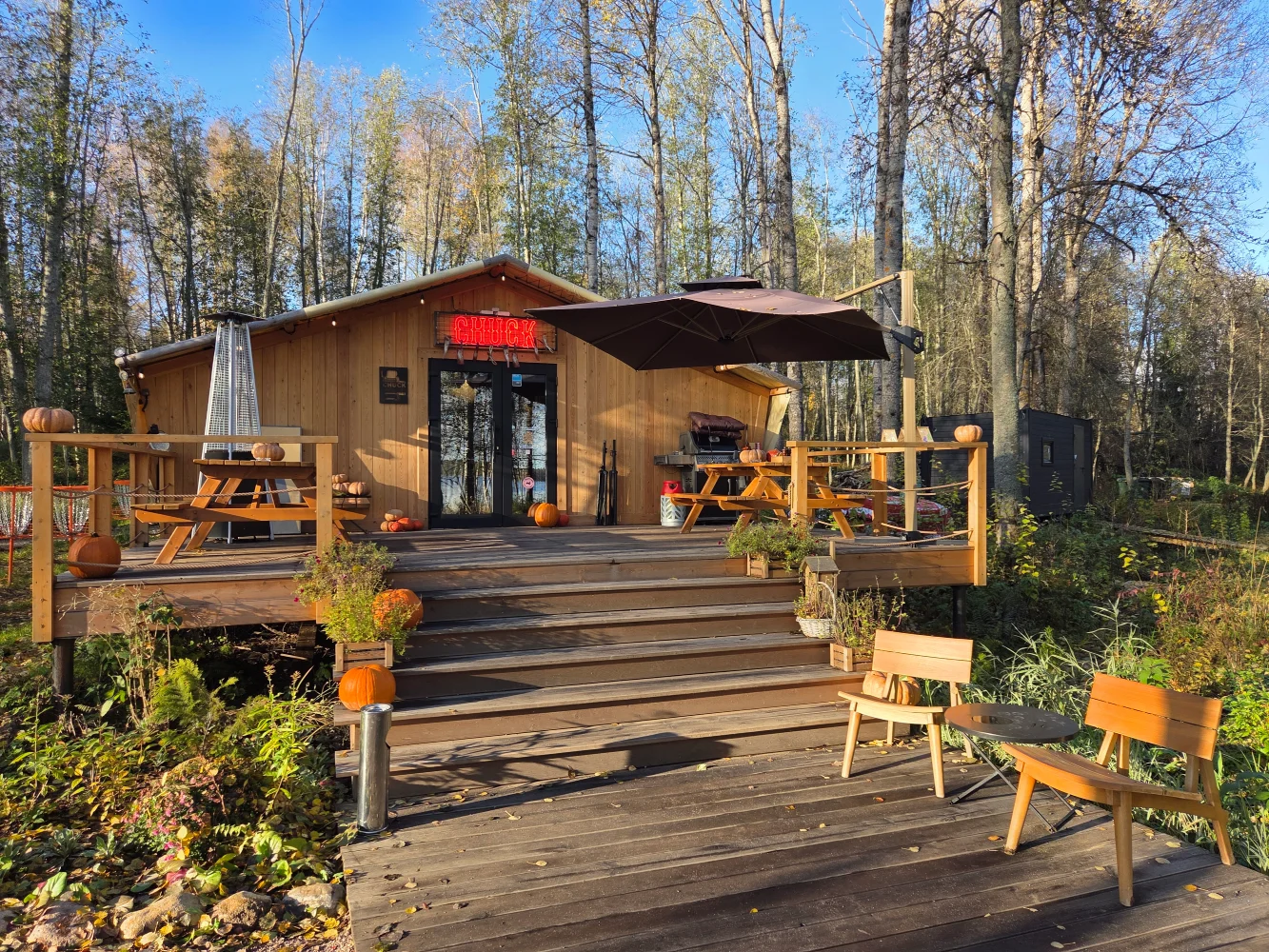 Zajednička drvena terasa Pati modela sa centralnim prilazom i mestima za sedenje u prirodnom okruženju.